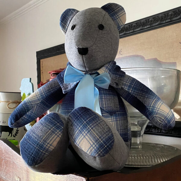 This blue and gray bear has a pocket and a light blue ribbon.
